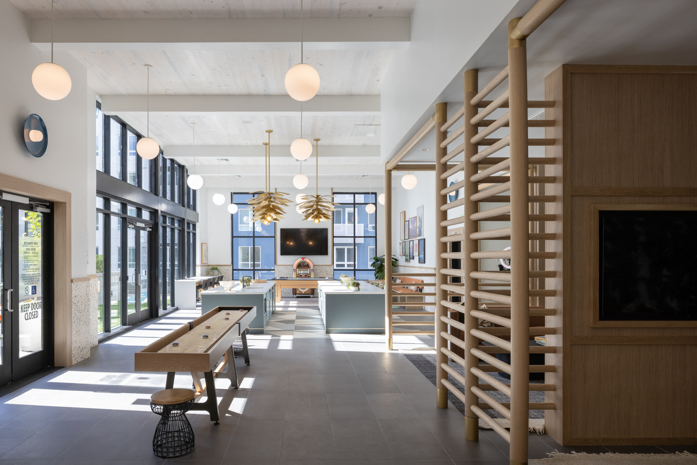 the lobby of a building with a staircase and tables and a television