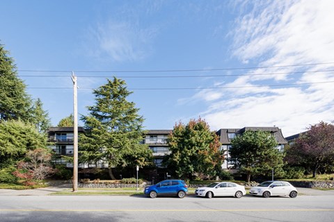 a city street with cars parked in front of an apartment building