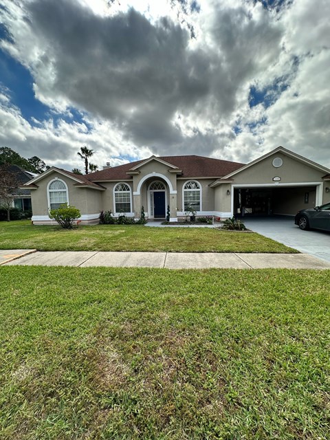 a house with a lawn and a cloudy sky