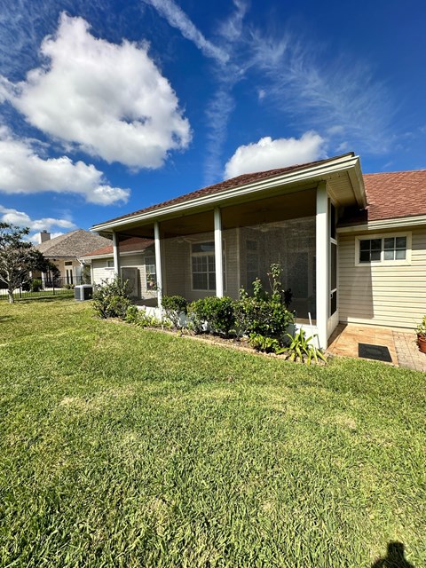 a house with a lawn and a blue sky with clouds