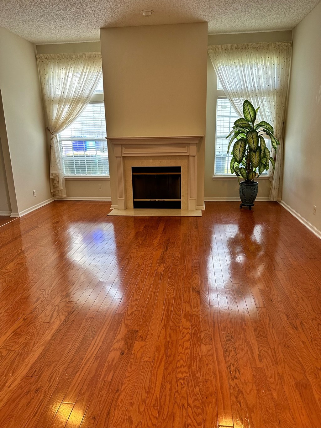 an empty living room with wood floors and a fireplace