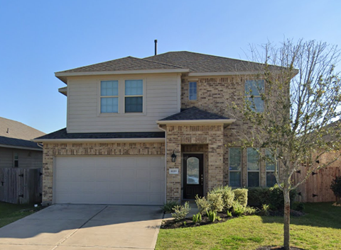A house with a garage and a tree in front.