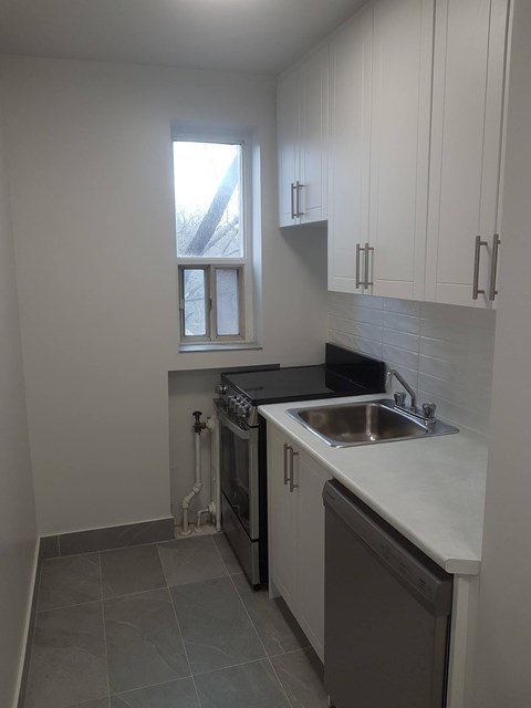 A kitchen with white cabinets and a black countertop.