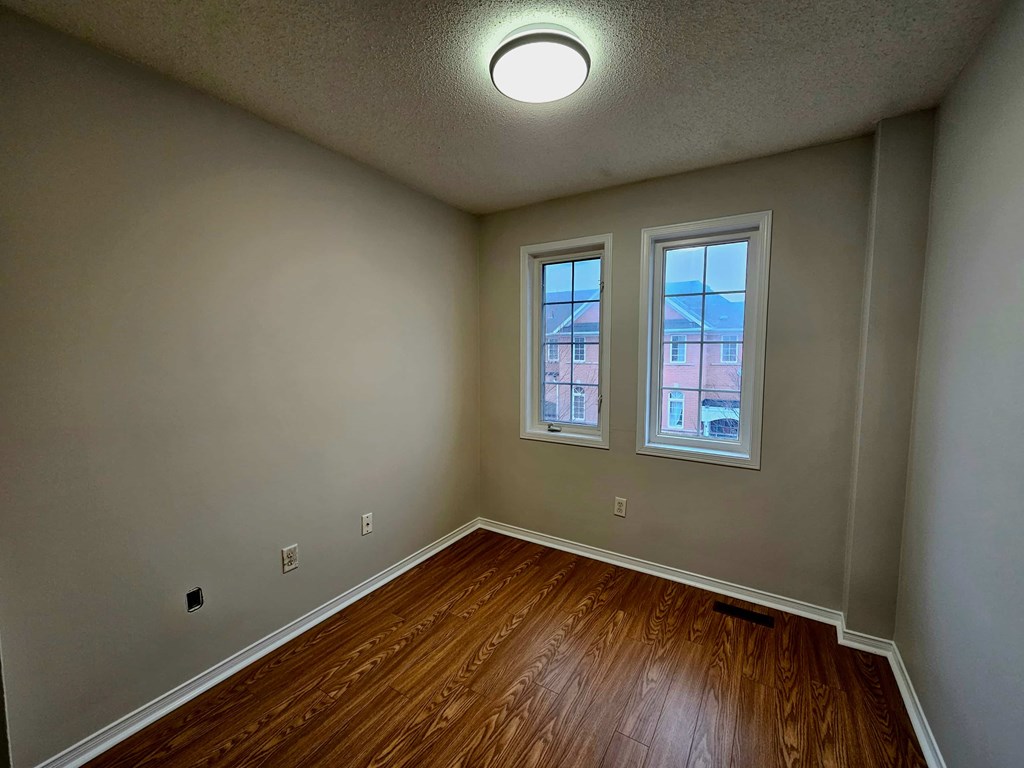 A room with a wooden floor and two windows.
