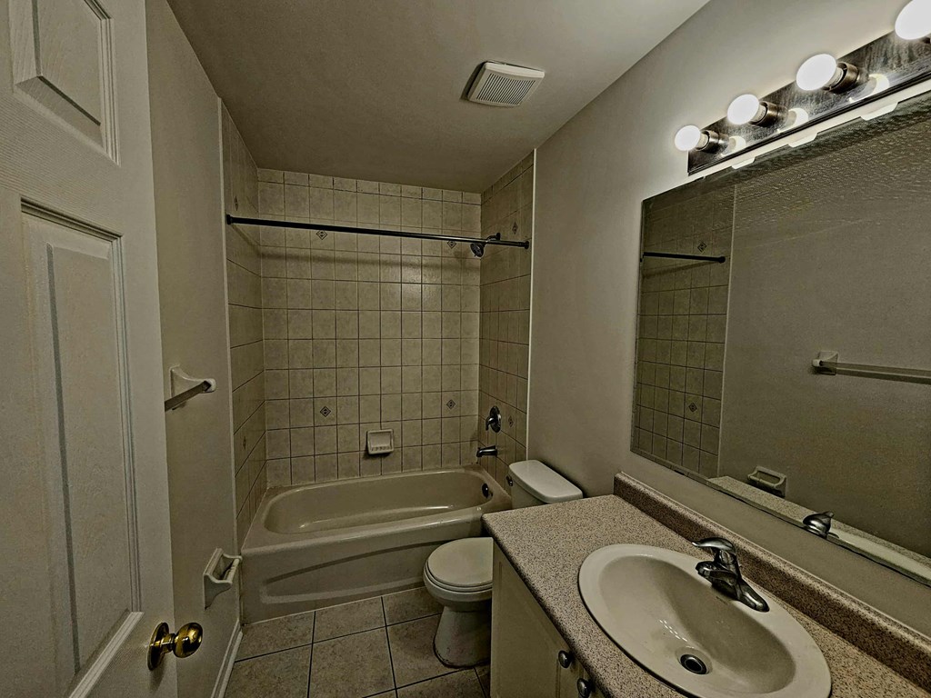 A bathroom with a white toilet, a sink, a bathtub, and a mirror.