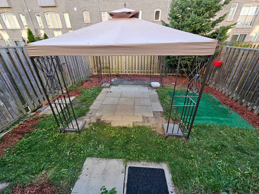 A patio with a tent and a table is surrounded by a fence.