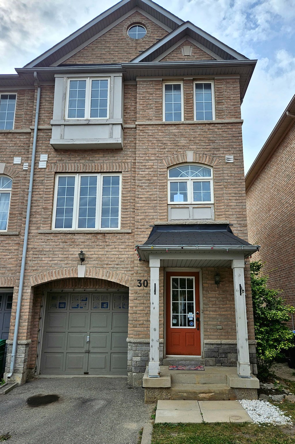 A brick house with a red door and a garage door.