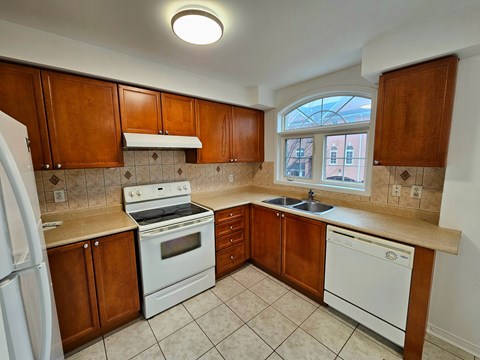 A kitchen with white appliances and brown cabinets.