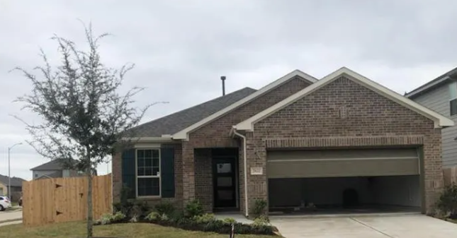 A house with a garage and a tree in front.