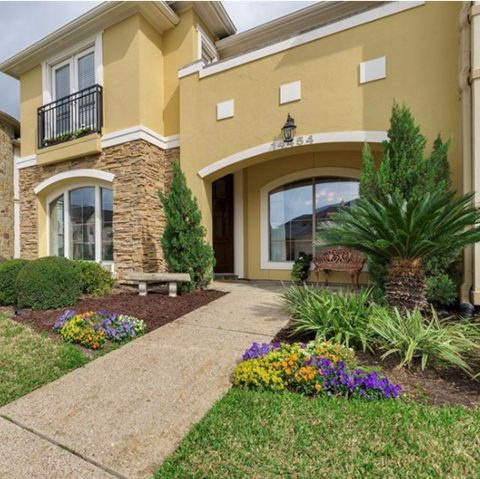 a walkway in front of a house with a garden