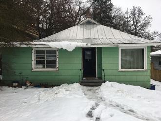 a green house with snow in front of it