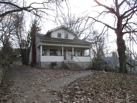 a small white house with a sidewalk in front of it