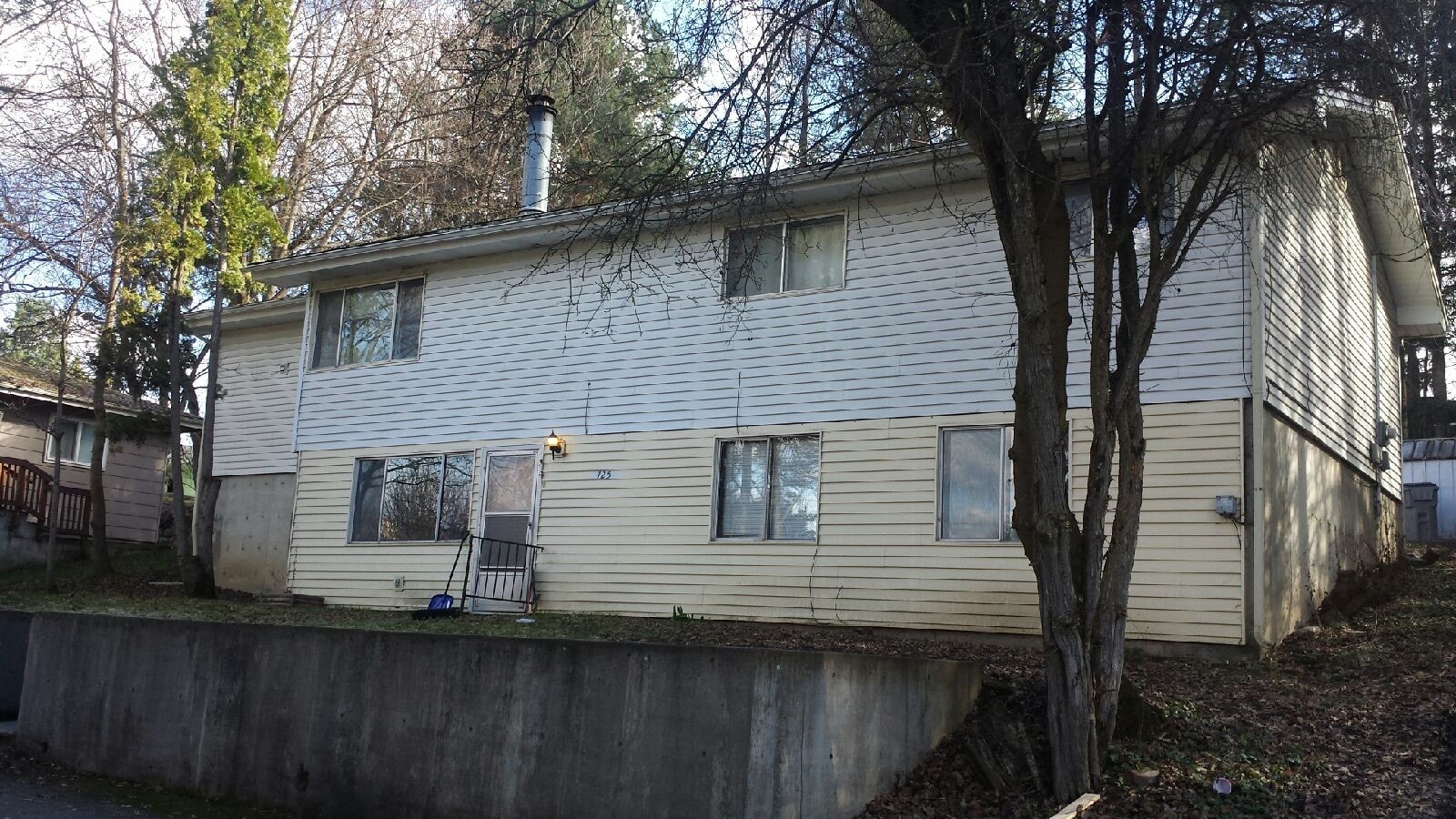 a white house with a fence in front of a tree