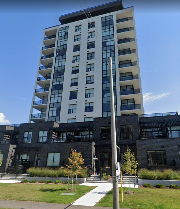 A modern multi-story building with a glass facade and a mix of white and dark grey balconies.