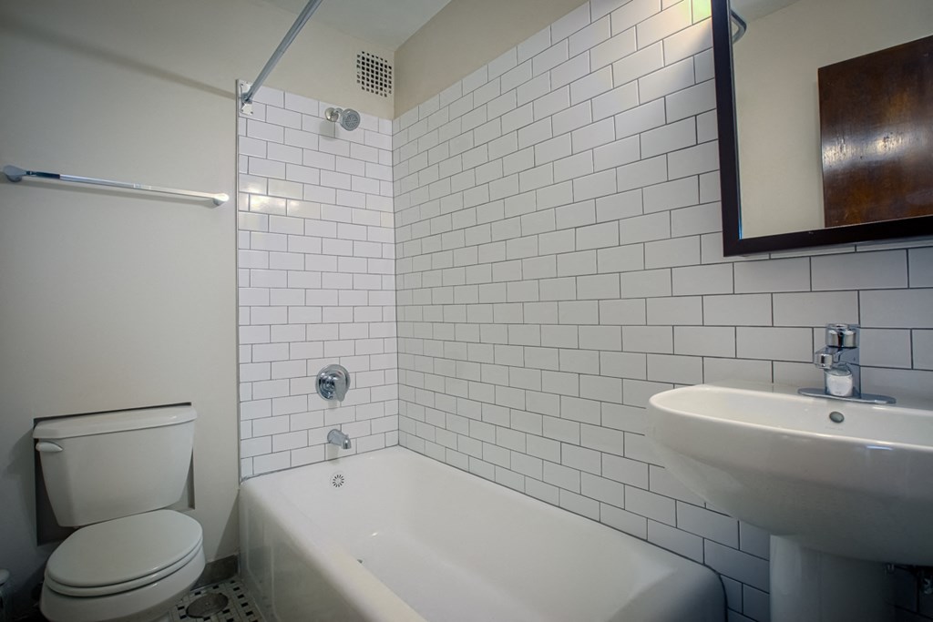 a white tiled bathroom with a toilet sink and tub