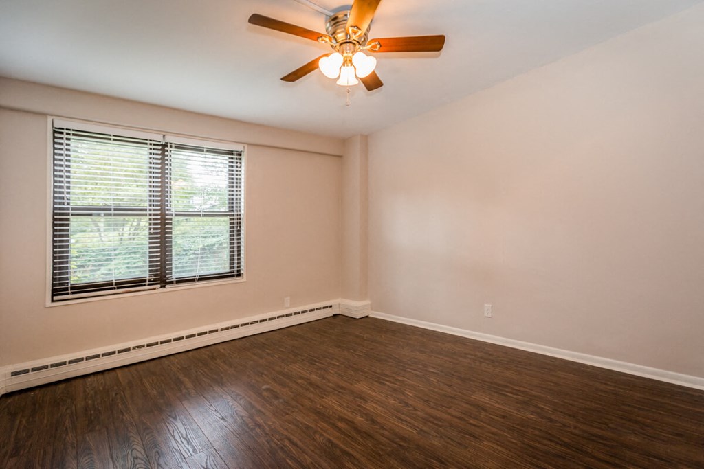an empty living room with wood floors and a ceiling fan