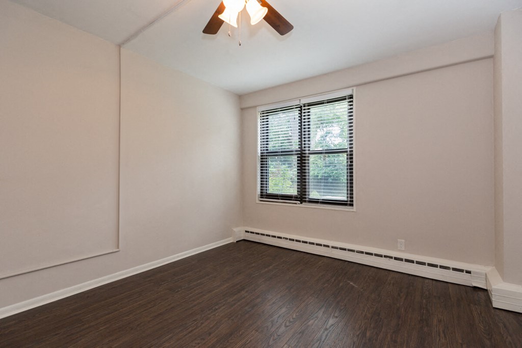 the living room of an empty home with wood flooring and a window