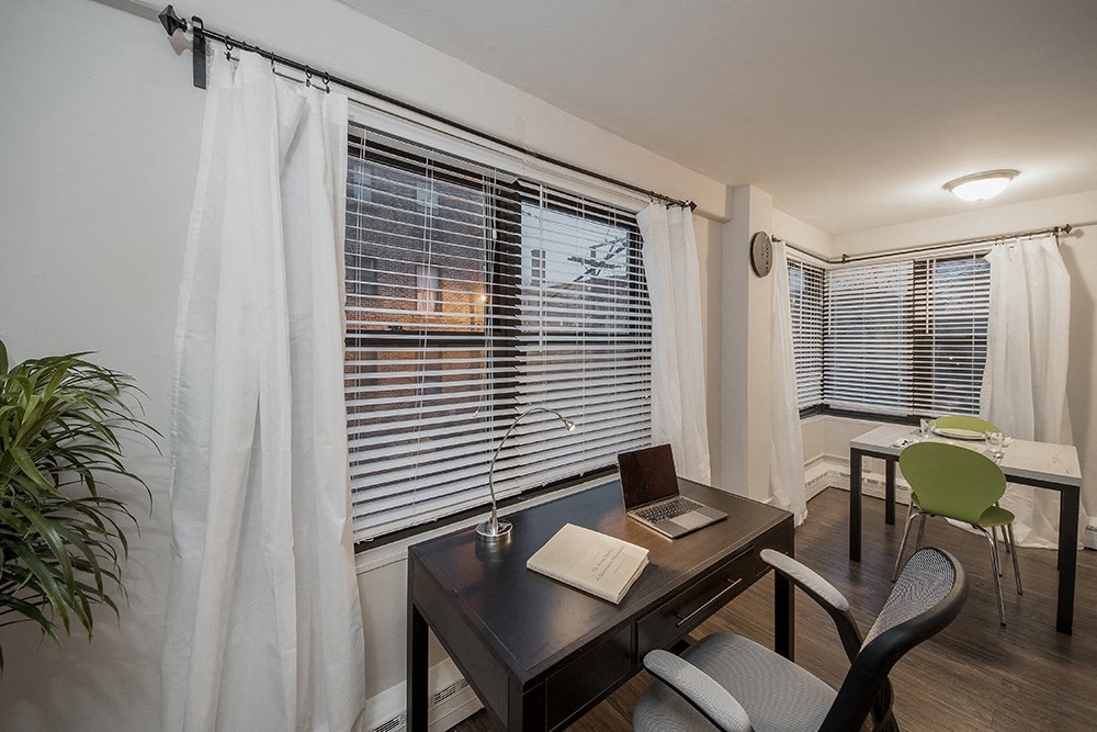 a home office with a desk and a window with blinds