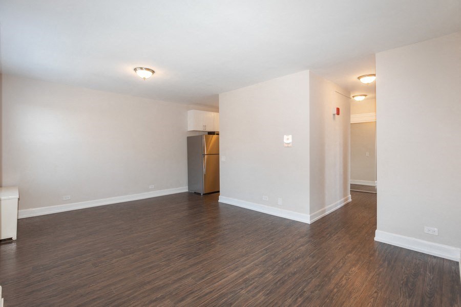 an empty living room with wood flooring and white walls