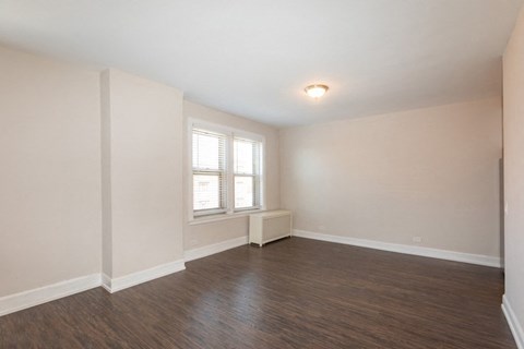 the spacious living room with wood flooring and a window
