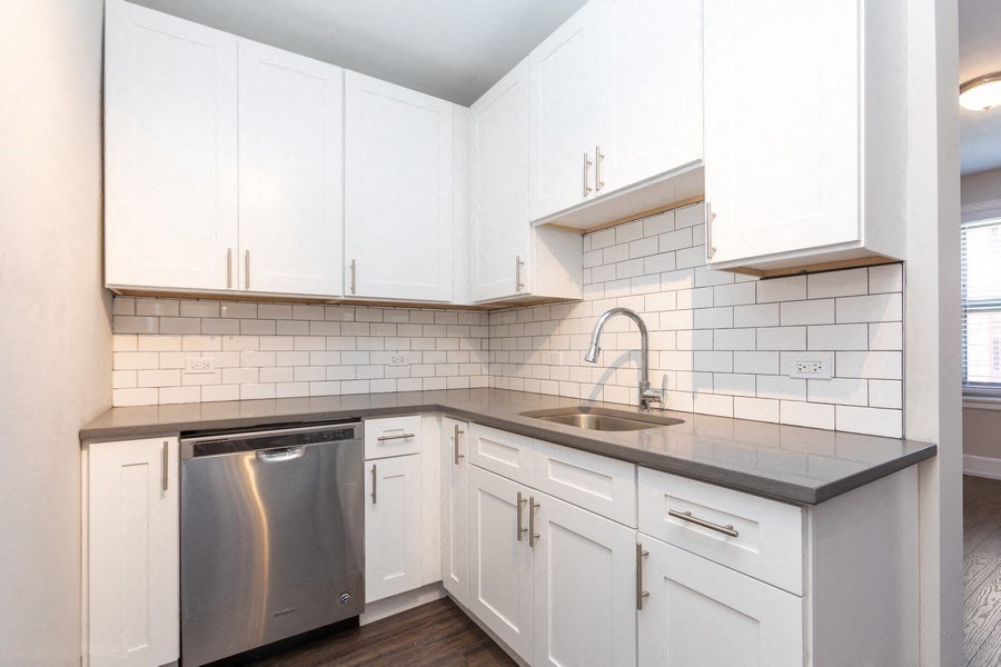 the kitchen of a home with white cabinets and a stainless steel dishwasher