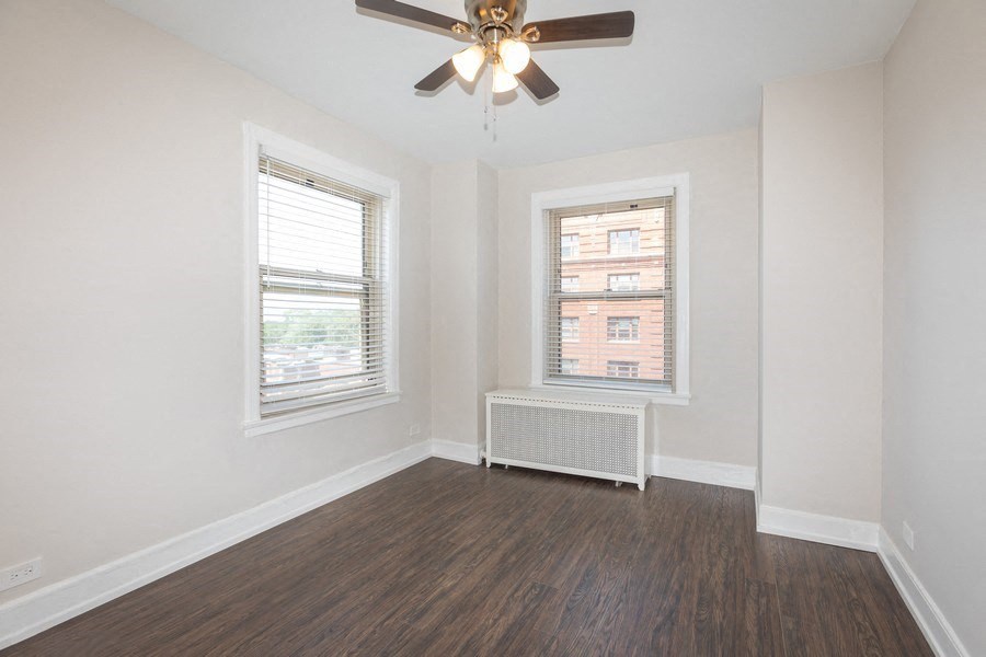 an empty living room with a ceiling fan and two windows