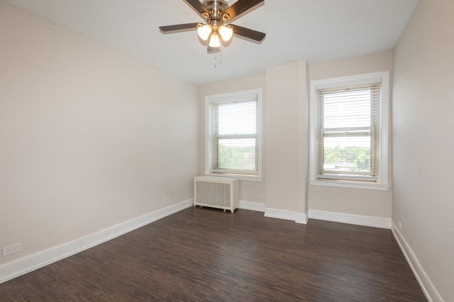 an empty living room with a ceiling fan and two windows