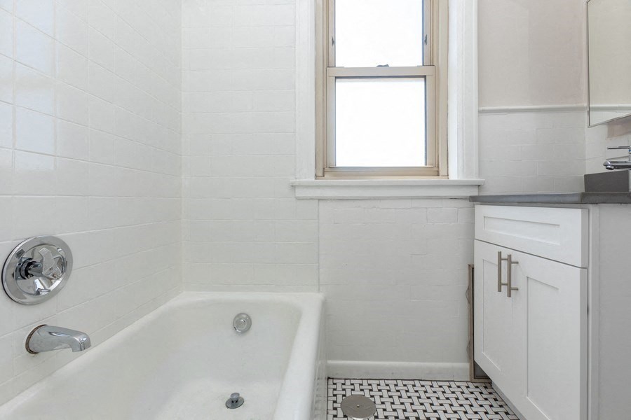 a white bathroom with a tub and a window