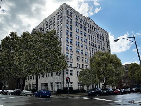 a tall building with cars parked in front of it on a city street