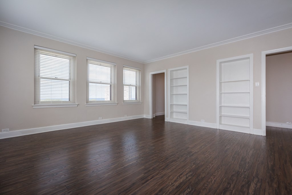 an empty living room with wooden floors and white doors