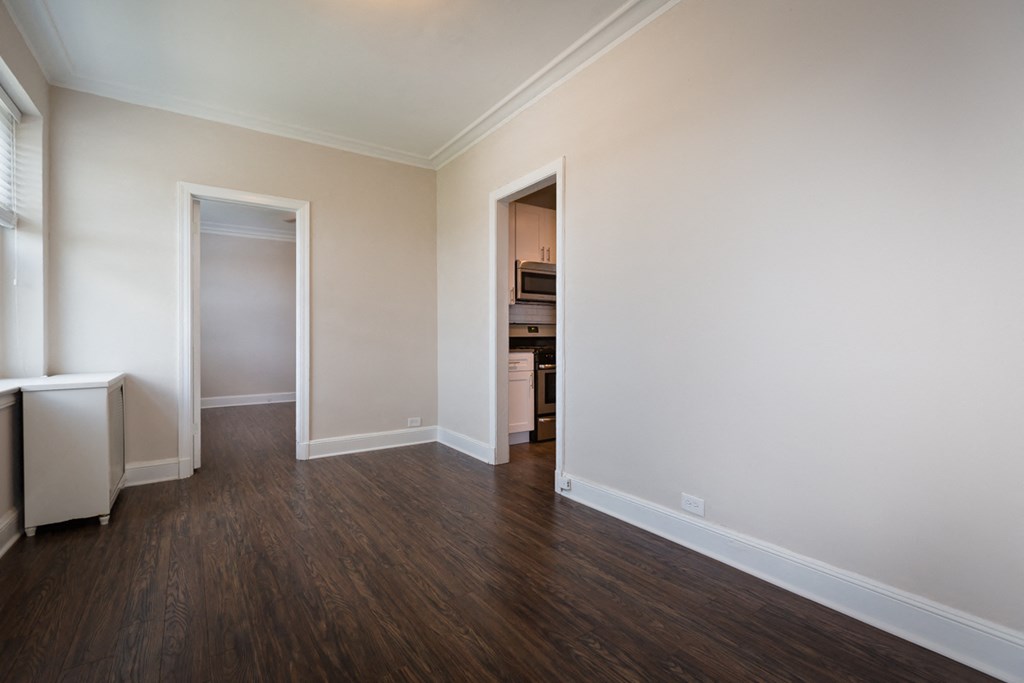 an empty living room with wooden floors and white walls