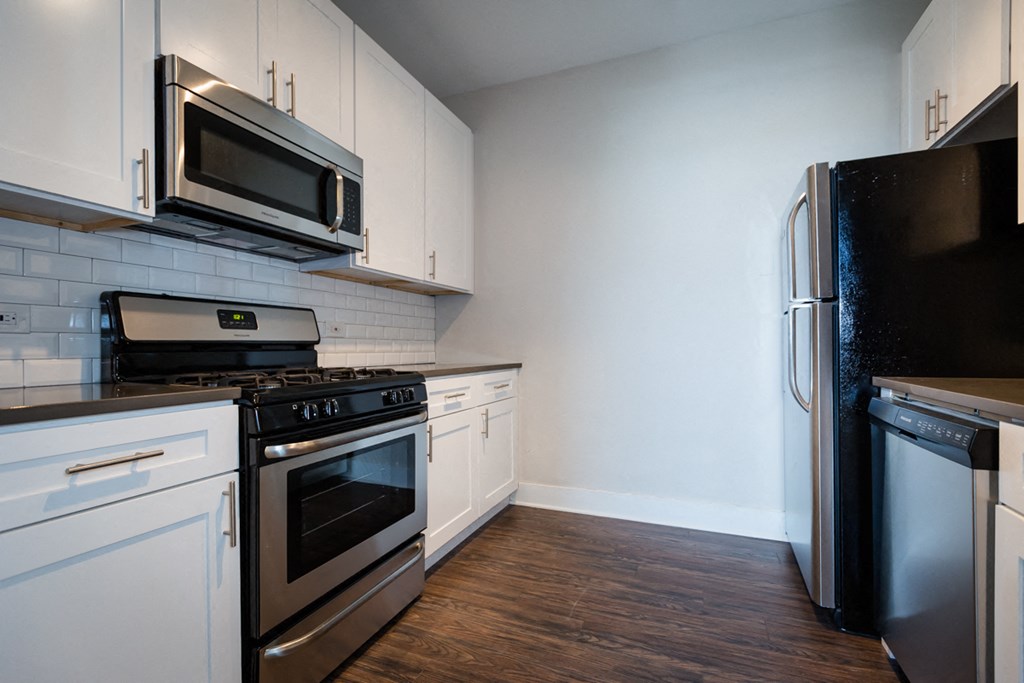 an empty kitchen with stainless steel appliances and white cabinets