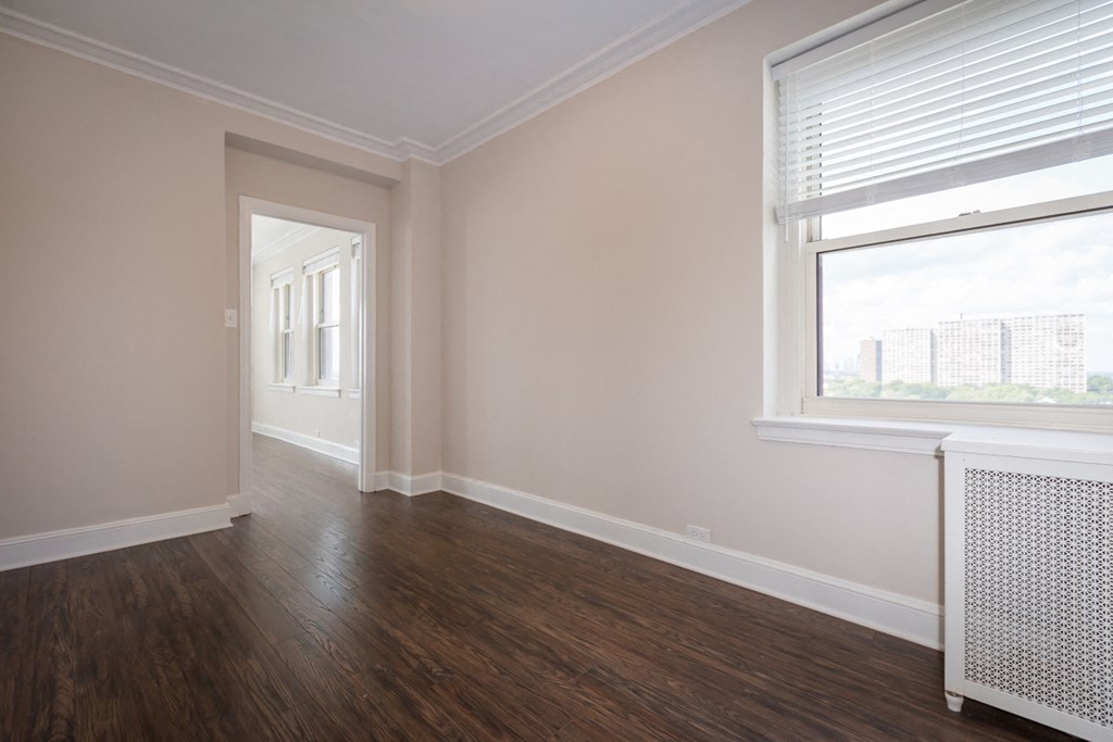 an empty living room with wood floors and a window