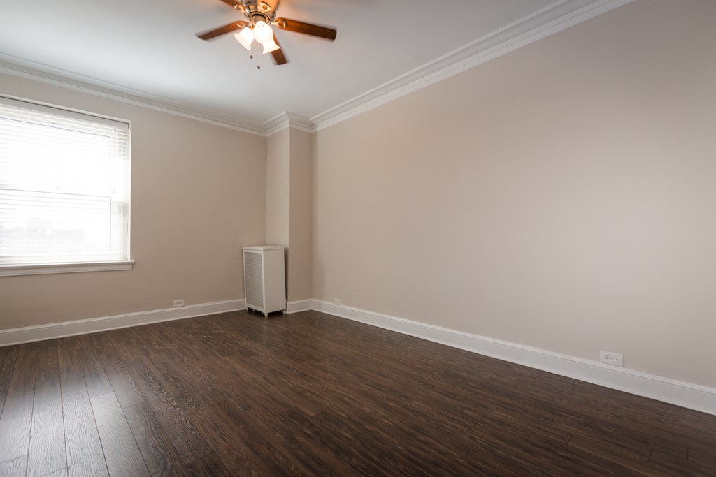 an empty room with wooden floors and a ceiling fan