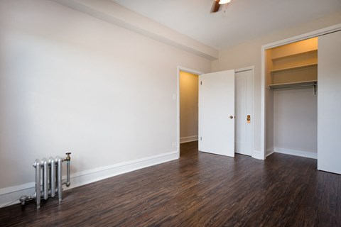 a living room with white walls and wood flooring and a closet