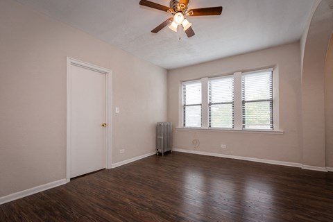 an empty living room with hard wood floors and a ceiling fan