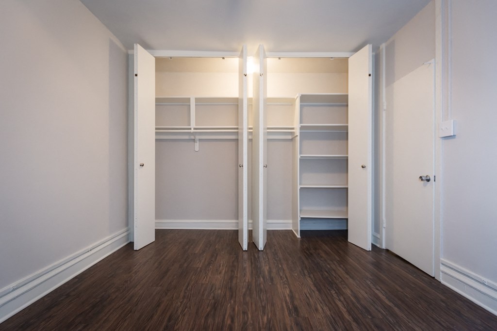 a bedroom with a closet and shelves and a wood floor