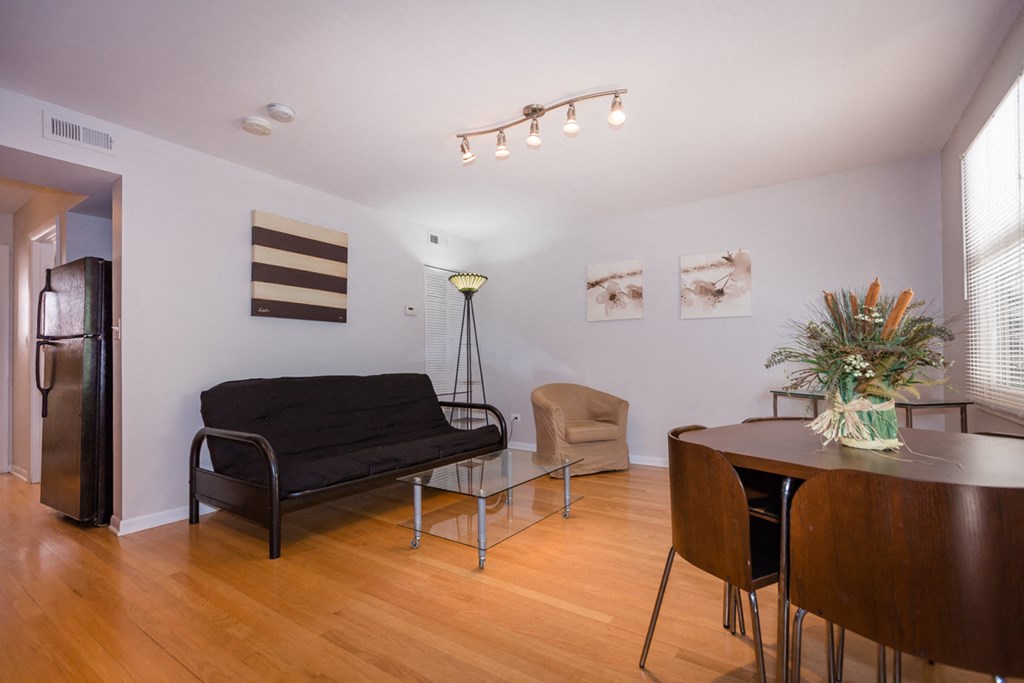 a living room and dining room with a table and a black couch