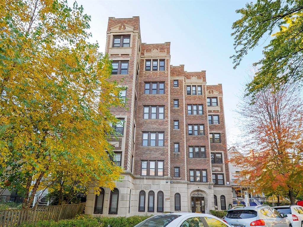 a tall brick building with cars parked in front of it