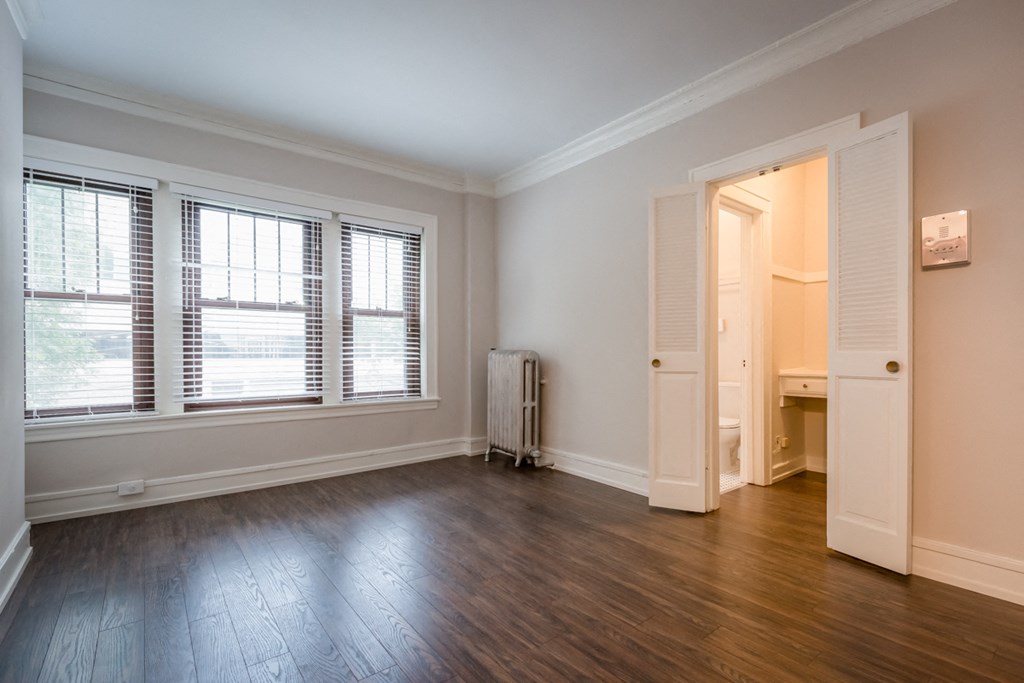 an empty living room with wood flooring and windows