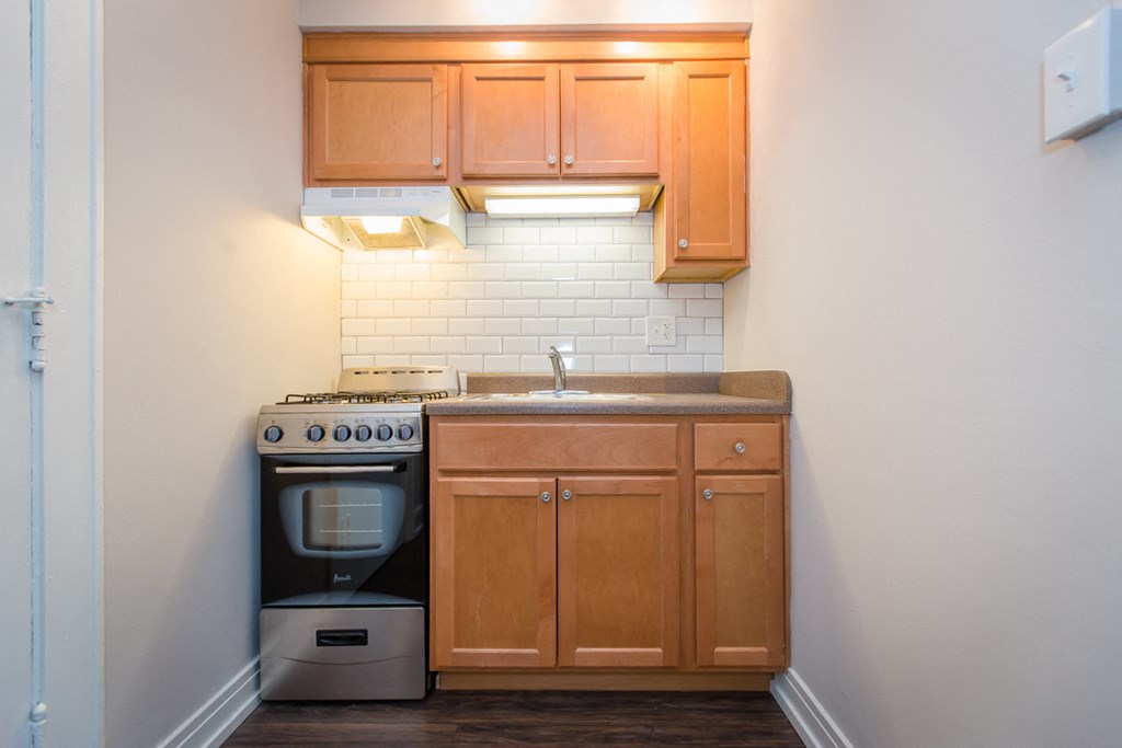 an empty kitchen with wooden cabinets and a stove and sink