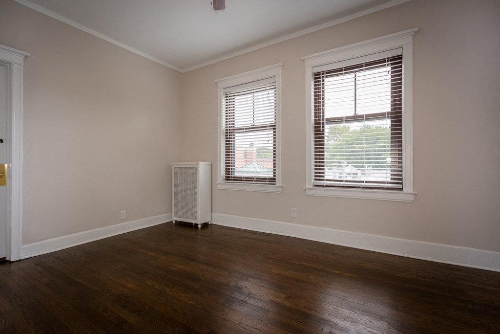 an empty living room with wood floors and two windows
