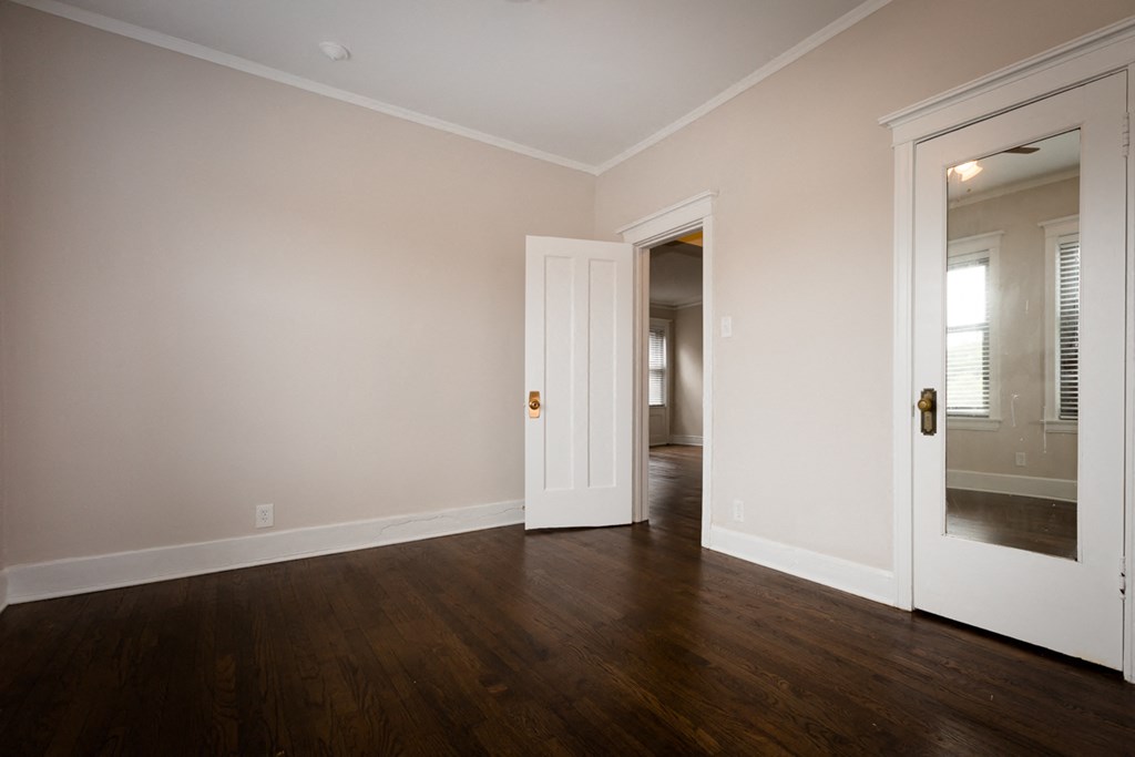 an empty living room with wood floors and white walls