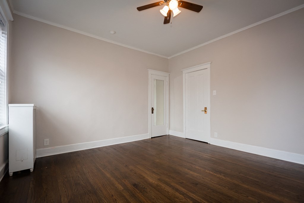 an empty living room with wood floors and a ceiling fan