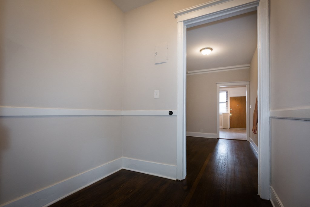 interior view of a living room and hallway with white walls and wood floors