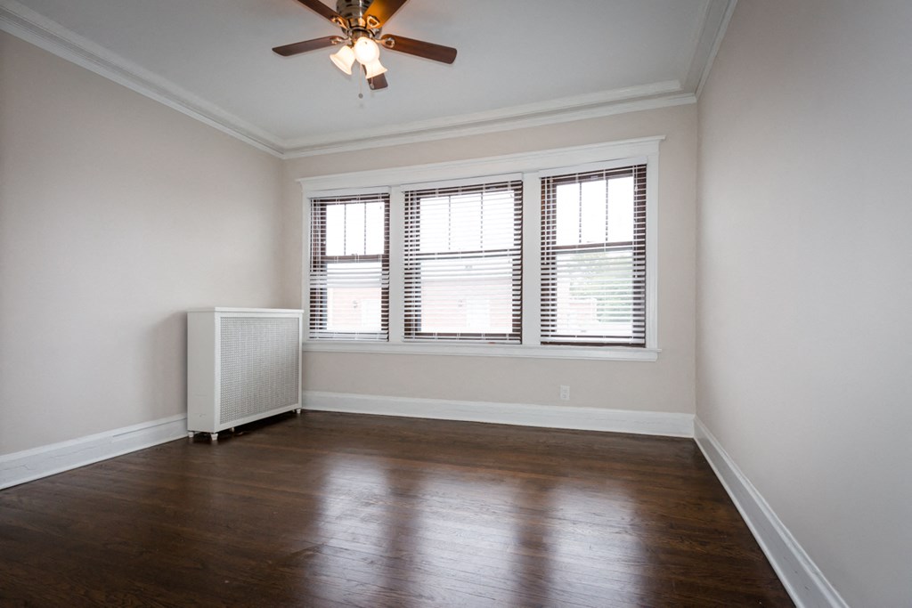 an empty living room with wood floors and a ceiling fan