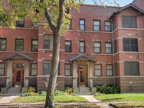 a red brick building with a tree in front of it
