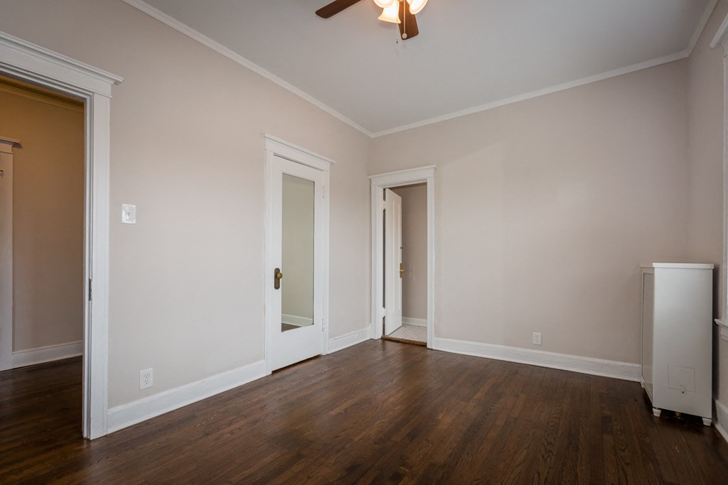 an empty living room with wood floors and a ceiling fan