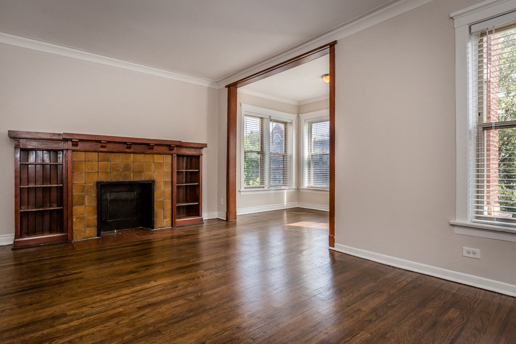 an empty living room with a fireplace and wooden floors