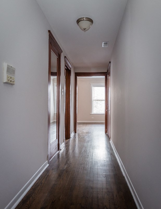 an empty hallway with wood floors and white walls